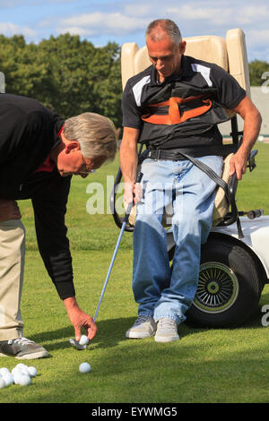 Instructor placing golf ball for man with a spinal cord injury Stock Photo