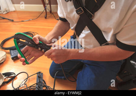 Cable installer using a crimping tool to add a new cable connector to a cable Stock Photo