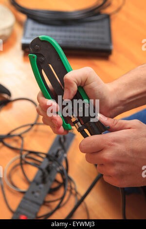 Cable installer using a crimping tool to add a new cable connector to a cable Stock Photo