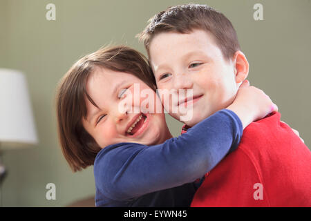 Little girl with Down Syndrome laughing with her brother Stock Photo