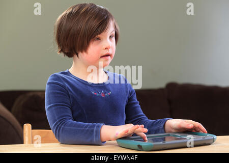 Little girl with Down Syndrome playing an electronic learning game Stock Photo