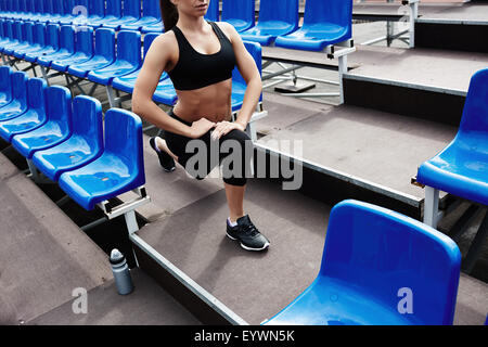 Fit woman in sportswear doing exercise for legs at stadium Stock Photo
