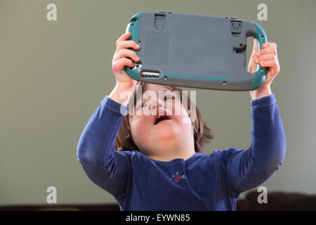 Little girl with Down Syndrome playing an electronic learning game Stock Photo