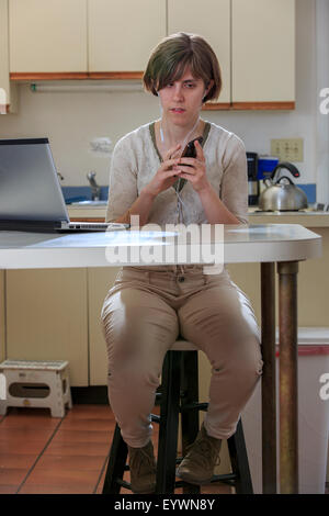 Blind woman using assistive technology ear plugs to listen to her cell phone Stock Photo