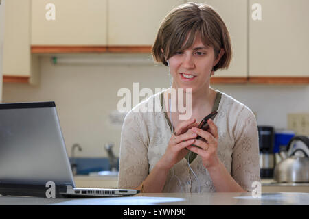 Blind woman using assistive technology ear plugs to listen to her cell phone Stock Photo