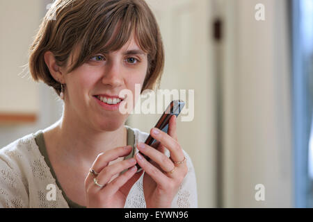 Blind woman using assistive technology to listen to texts on her cell phone Stock Photo