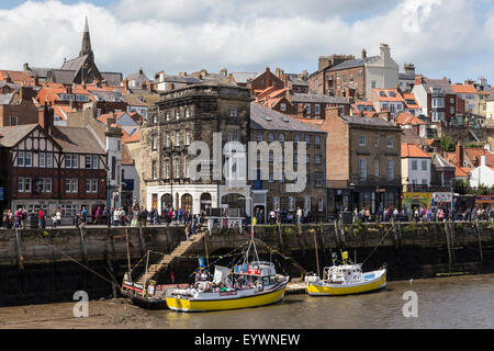 Boats moored on the West Side of the River Esk and passers-by on Pier Road, Whitby, North Yorkshire, Yorkshire, England, UK Stock Photo