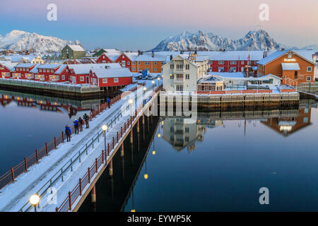 Hikers admire sunset colors on the typical red houses from a deck, Svolvaer, Lofoten Islands, Arctic, Norway, Scandinavia Stock Photo
