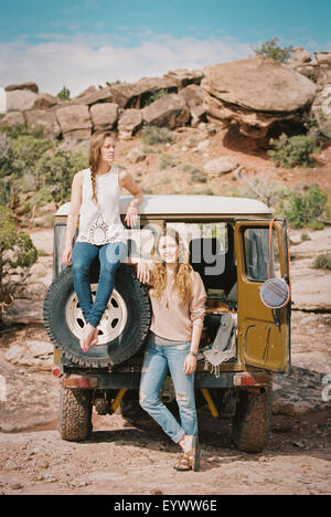 Two women standing by a 4x4 on a mountain road. Stock Photo