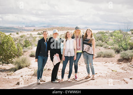 Group of five women, friends standing side by side in a desert landscape smiling. Stock Photo