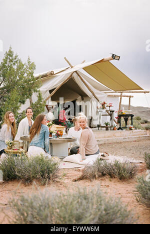 A group of women, friends sitting on the ground round a table having a meal. Stock Photo