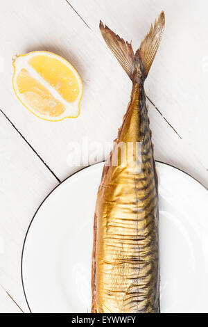 Smoked mackerel on white plate with lemon. Stock Photo