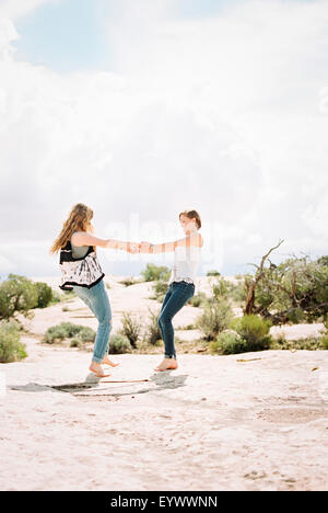 Two barefoot woman holding hands, dancing Stock Photo