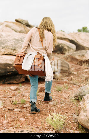 Woman walking in a desert carrying a leather bag. Stock Photo