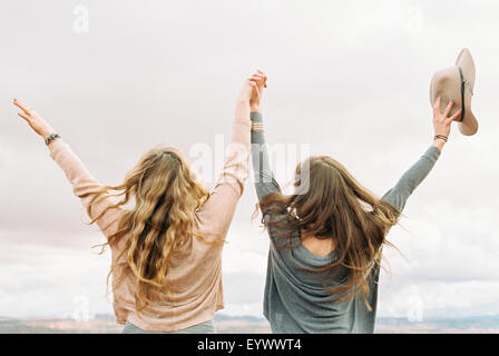 two women with their arms raised up in the air. Stock Photo