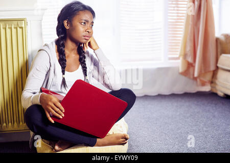 Frustrated ethnic girl sat indoors Stock Photo