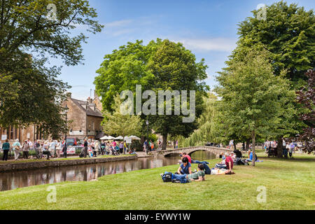 Tourists on a day out on a summer afternoon in the Cotswold village of Bourton-on-the-Water, Gloucestershire, England. Stock Photo