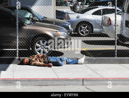 Los Angeles, CA, USA - September 23, 2011: Homeless man sleeps on the street near the fence in the center of Los Angeles Stock Photo