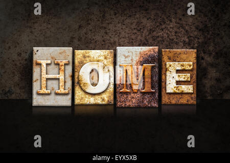 The word 'HOME' written in rusty metal letterpress type on a dark textured grunge background. Stock Photo