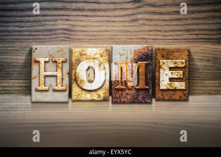 The word 'HOME' written in rusty metal letterpress type sitting on a wooden ledge background. Stock Photo