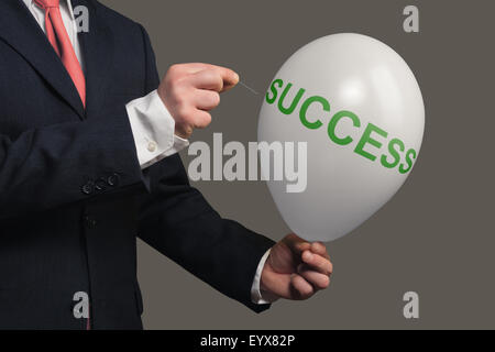 Man in Suit lets a Dream burst with a needle Stock Photo
