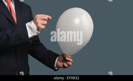 Businessman in Suit lets a Balloon burst with a needle Stock Photo