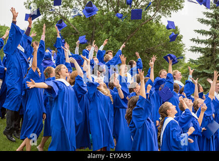 Graduates tossing caps in air, at a high school graduation ceremony. Stock Photo