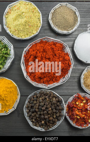 Various spices in shiny bowls on a dark wooden table Stock Photo