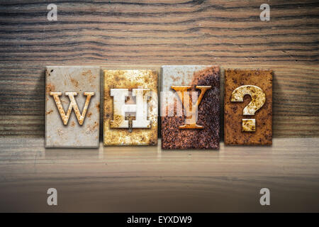 The word "WHY?" written in rusty metal letterpress type sitting on a wooden ledge background. Stock Photo