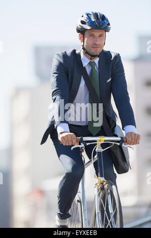 Businessman in suit commuting on bicycle with helmet Stock Photo
