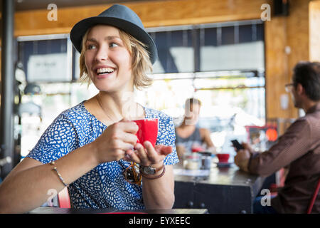 Smiling woman drinking coffee looking over shoulder in cafe Stock Photo