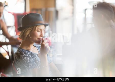 Woman in hat drinking coffee in cafe Stock Photo