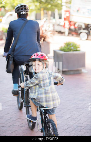 Portrait smiling boy riding tandem bicycle with businessman father Stock Photo