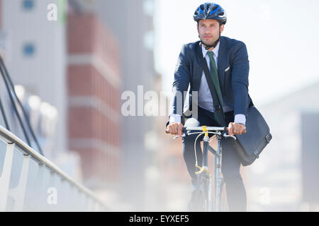Businessman in suit and helmet riding bicycle in city Stock Photo