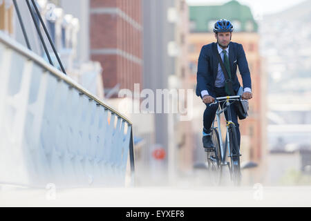 Businessman in suit and helmet riding bicycle in city Stock Photo
