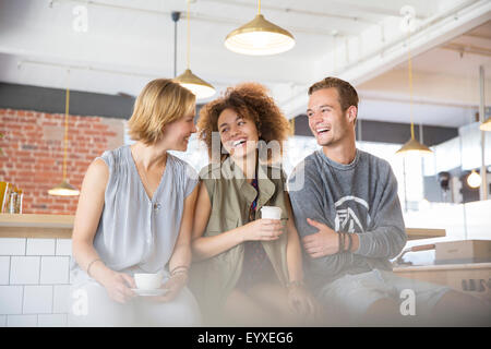 Laughing friends drinking coffee in cafe Stock Photo