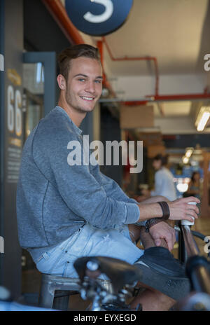 Image of young happy man sitting in cafe outdoors while using mobile ...