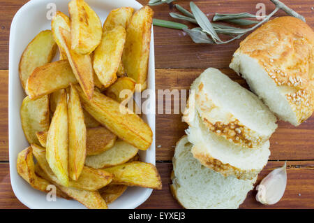 Homemade fried potatoes on a plate decorated with sliced bread, onion, and a tomato Stock Photo