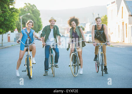 Portrait smiling friends sitting on bicycles on road Stock Photo