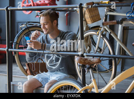 Young man texting with cell phone near bicycles at railing Stock Photo