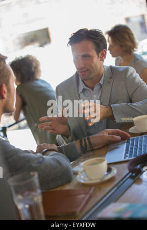 Businessmen talking and gesturing at cafe Stock Photo