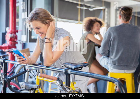 Smiling woman texting with cell phone at railing above bicycle
