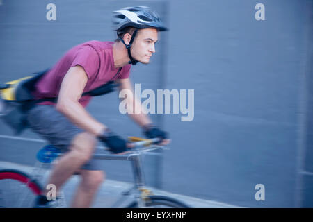 Focused bicycle messenger with helmet on the move Stock Photo