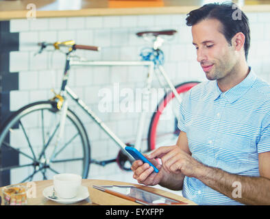 Man texting with cell phone near bicycle in cafe Stock Photo