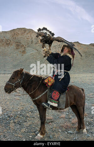 Kazakh eagle hunter with his un-hooded golden eagle held high #1, west of Olgii, Western Mongolia Stock Photo