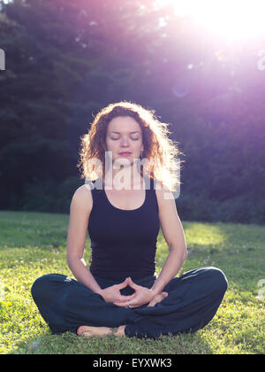 License available at MaximImages.com - Woman meditating in the nature sitting on grass in sunlight Stock Photo