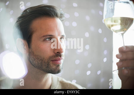 Close up serious man examining white wine Stock Photo