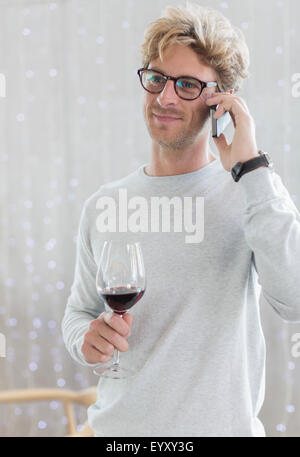 Man drinking red wine and talking on cell phone Stock Photo