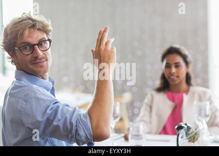 Man gesturing for service at restaurant table Stock Photo