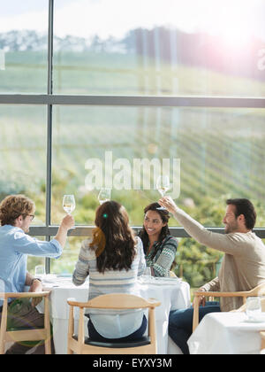 Friends toasting wine glasses in winery dining room Stock Photo